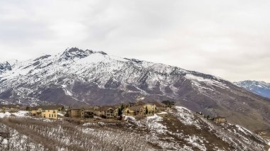 Kışın bakıldığında yapraksız ağaçlar çok katlı evler ve yol ile Panorama çerçeve Karlı dağ