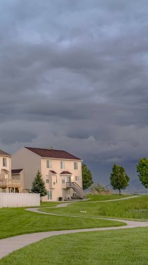 Döşeli bir yol ve gölet ile geniş bir yeşil alana bakan Dikey Ev cephe