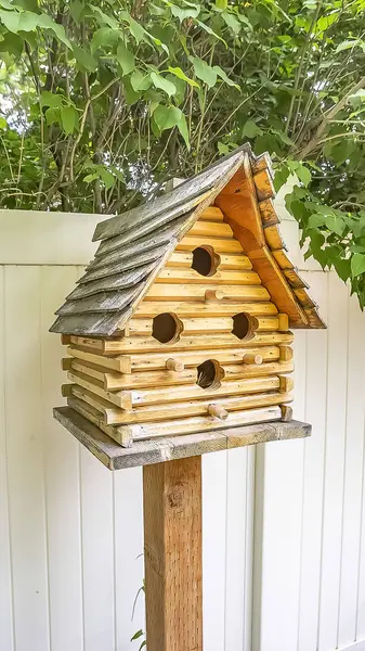 Verticale close-up van houten birdhouse met verschillende entree gaten op de werf van een huis — Stockfoto