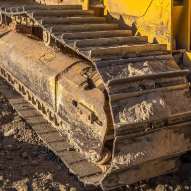 Kare çerçeve Güneşli bir günde sarı bir inşaat makinesi Kirli metal parça ped.