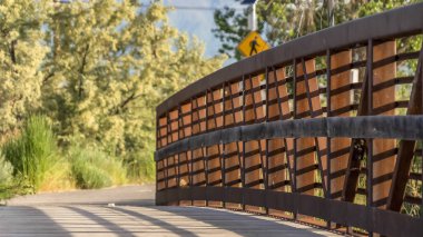 Güneşli bir günde metal korkuluk ve ahşap güverte ile bir köprü kapatın