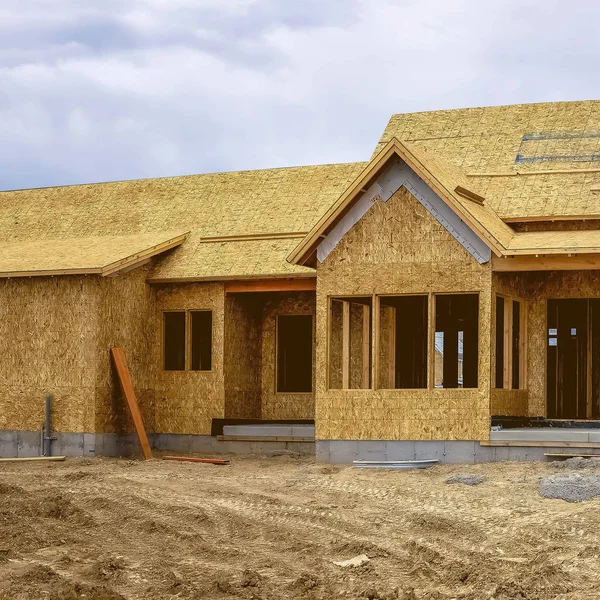 Quadratische Hausfassade im Bau gegen verschneiten Berg und bewölkten Himmel — Stockfoto