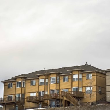 Bulutlu gökyüzü altında balkon ve yarım altıgen şekilli pencereler ile Kare çerçeve Evler