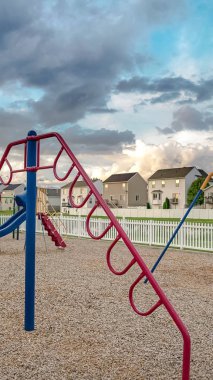 Bulutlu gökyüzüne karşı bir mahalle oyun alanında Dikey Tırmanma çubukları salıncaklar ve slaytlar