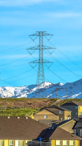 Vertical frame Homes with snow covered mountain and electricity tower in the background