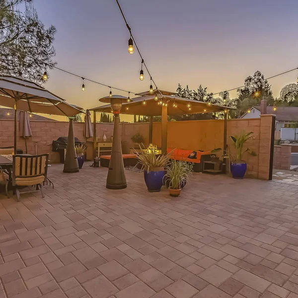 çerçeve Dize ışıkları ile aydınlatılmış bir taş tuğla veranda üzerinde yemek ve oturma alanı