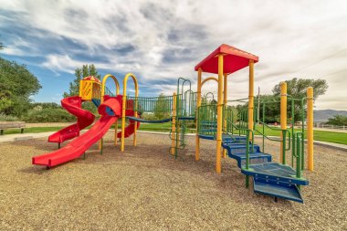 Ağaçlar ve uzak dağ manzaralı rahatlatıcı bir parkta Çocuk oyun alanı