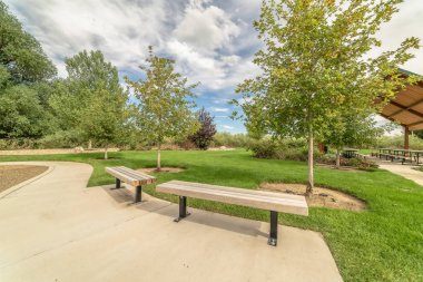 Arka planda patika ve piknik köşkü boyunca ahşap banklar ile Park