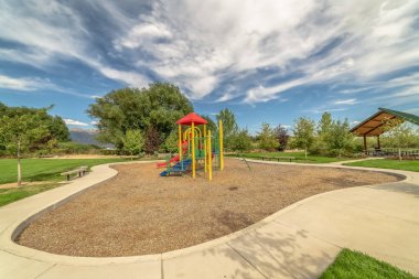 Mavi gökyüzü ve bulutlar altında çocuk oyun alanı ve piknik pavyonu ile Park