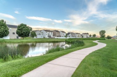 Merdiven ve balkonlu evlerin önündeki parkta parlak gölet ve geçit