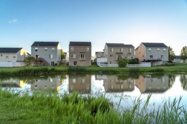 Evler güneşli bir günde mavi gökyüzü havai ile parlak bir gölet yansıyan