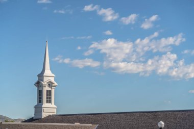 Mavi gökyüzü ve bulutlar arka plan ile bir kilisenin beyaz çan kulesi ve karanlık çatı