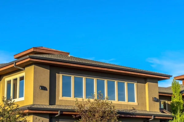 Planta superior de una casa forrada de ventanas rectangulares contra el cielo azul claro — Foto de Stock
