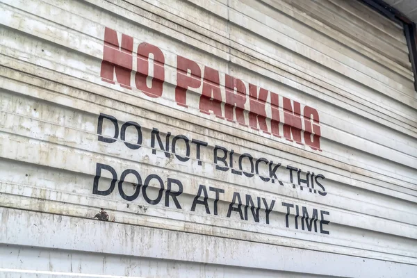 Close up of No Parking sign painted on the corrugated metal door of a building — Stock Photo, Image