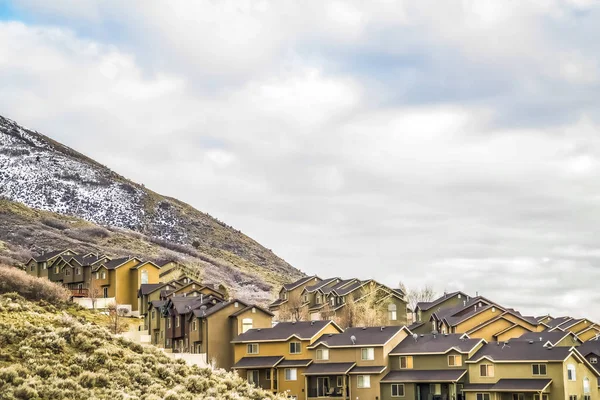 Row of houses built on the slope of a mountain with cloudy blue sky background