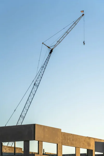 A befejezetlen épület betonszerkezete fölé magasodó építőipari daru — Stock Fotó