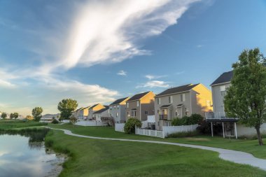 Bulutlu mavi gökyüzü güneşli bir günde evlerin önünde parlak bir gölet yansıyan