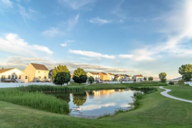 Güneşli bir günde doğal bir mahallede bulutlu mavi gökyüzünü yansıtan parlak gölet