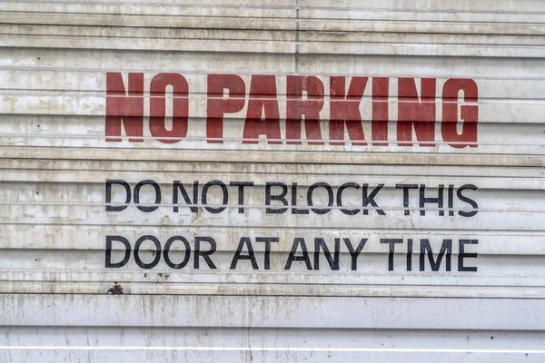 Fechar de uma porta de metal ondulado com um sinal de estacionamento pintado — Fotografia de Stock