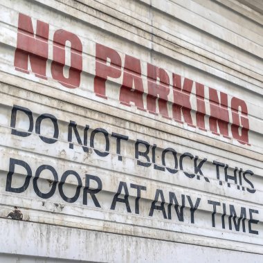 Kare çerçeve Bir binanın oluklu metal kapı boyalı No Park işareti yakın