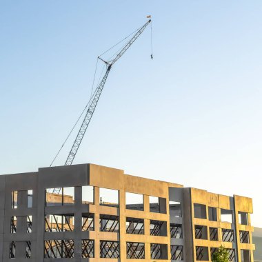 Mavi gökyüzüne karşı metal çubuklarla desteklenen bitmemiş bir binanın kare çerçeve çerçevesi