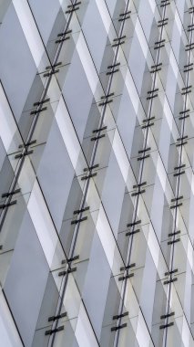 Parlak beyaz gökyüzüne karşı çok katlı bir binanın dış dikey yakın görünümü