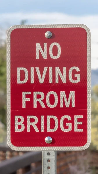 Cierre vertical de un cartel de No Buceo junto a un puente con barandilla de metal marrón — Foto de Stock