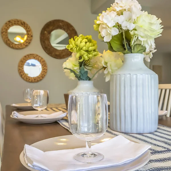 Square frame Dinner setting inside the dining room of a home with mirrors and wall background