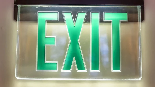 Marco panorámico Interior del edificio con una luz verde neón Signo de salida saltado en la pared blanca — Foto de Stock