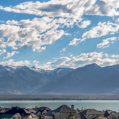 Mavi bir göle ve yükselen dağa bakan evleri ile Kare Pitoresk manzara