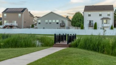 Evlerin önündeki parkta bir göletin üzerinden geçen bir köprüye giden Panorama çerçeve Yolu