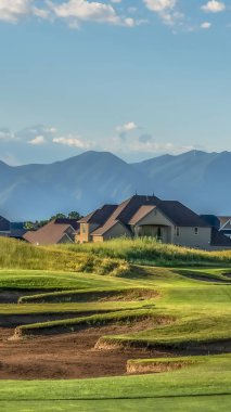 Arka planda evler ve dağ ile Dikey çerçeve Golf sahası güneşli bir günde görüntülenen