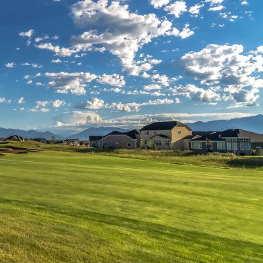 Arka planda evler ve dağ manzaralı bir golf sahası Kare çerçeve Fairway