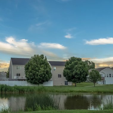 Arka planda evleri ile çimenli bir arazi üzerinde parlak bir gölet boyunca Square Pathway