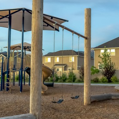 Evlerve bulutlu gökyüzüne karşı slaytlar ve salıncaklar ile Kare Mahalle oyun alanı