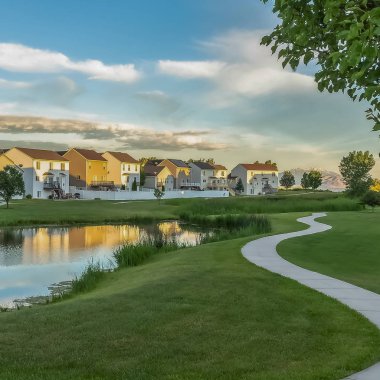 Kare çerçeve Yol ve bulutlar ile mavi gökyüzü altında yeşil otlar ile kaplı bir parkta gölet