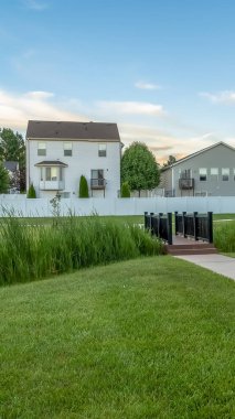 Evlerin önündeki parkta bir göletin üzerinden geçen bir köprüye giden dikey çerçeve Yolu