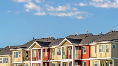 Panorama çerçeve Güneşli bir günde görüntülenen krem ve kırmızı duvar ile townhomes üzerinde bulutlu mavi gökyüzü