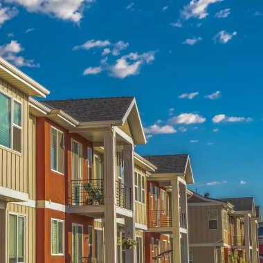 Güneşli bir günde bulutlu mavi gökyüzüne karşı beyaz ve turuncu dış duvar ile Square Homes