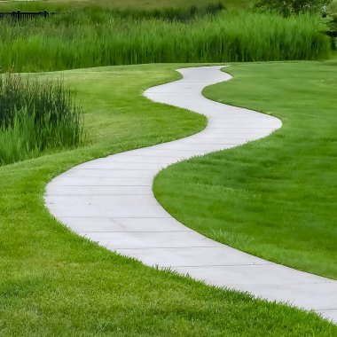 Kare Gölet ve bulutlu gökyüzü altında güneşli evlerin önünde doğal bir parkta yol