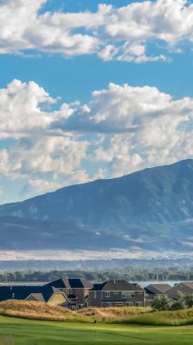 Dikey çerçeve Sakin mavi bir gölün yanında inşa edilmiş evler ve golf sahası ile güzel sahne