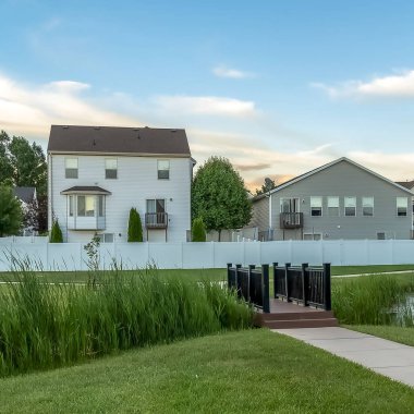 Kare çerçeve Yolu evlerin önünde bir parkta bir gölet üzerinden geçer bir köprü ye giden