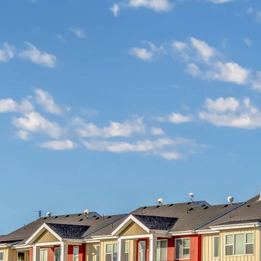 Kare çerçeve Güneşli bir günde görüntülenen krem ve kırmızı duvar ile townhomes üzerinde bulutlu mavi gökyüzü