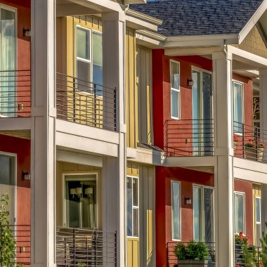 Güneşli bir günde gökyüzüne karşı kırmızı ve krem dış duvar kombinasyonu ile Square Homes