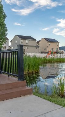 Evleri ve dağ arka plan ile bir mahalle parkı üzerinde bir gölet üzerinde Dikey çerçeve Köprü