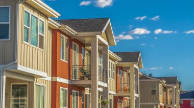 Güneşli bir günde bulutlu mavi gökyüzüne karşı beyaz ve turuncu dış duvarlı Panorama Homes