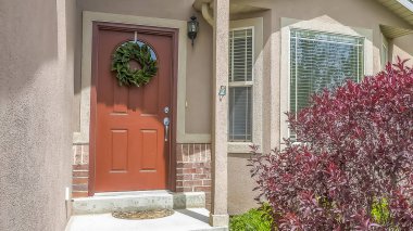 Çelenk ile süslenmiş kahverengi ön kapı ile bir evin girişinde Panorama çerçeve Merdivenler