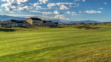 Arka planda ev ve dağ manzaralı bir golf sahası Panorama çerçeve Fairway