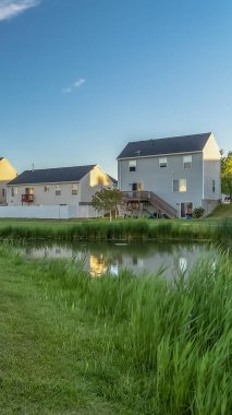 Mavi gökyüzü ve bulutlar altında güzel aile evleri önünde Dikey çerçeve Gölet ve yemyeşil alan