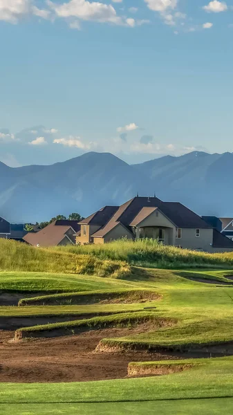 Vertikalrahmen-Golfplatz mit Häusern und Berg im Hintergrund an einem sonnigen Tag — Stockfoto